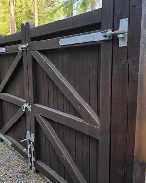 Wooden gate with metal latches and locks, surrounded by gravel. Price tags visible.