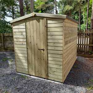 Wooden garden security shed surrounded by trees, with a gravel ground and a fenced area.