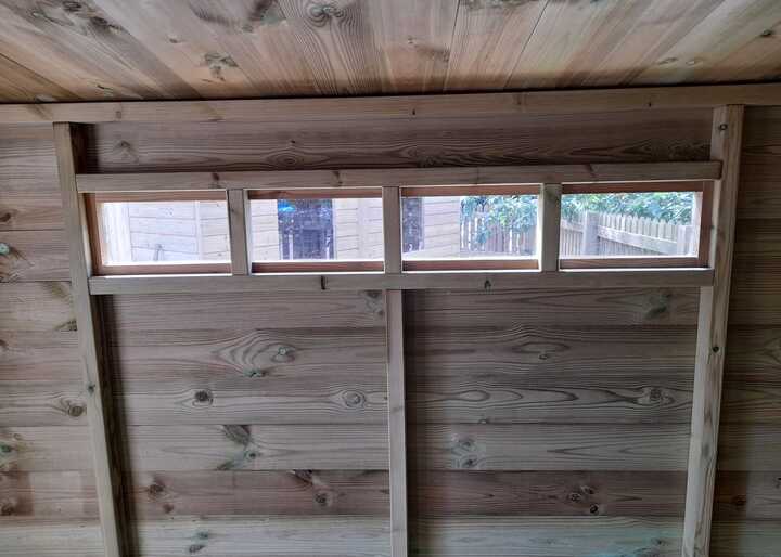 Interior view of a wooden shed with four horizontal windows.