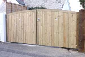 A pair of wooden arched gates stand closed in a stone-paved entrance.