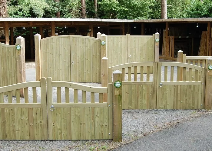 Timber driveway gates arranged in a landscaped area, surrounded by trees.