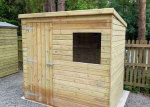 Wooden pent shed with a door and window, surrounded by trees and gravel.