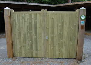 Wooden double gates with a lock, set within a fence, on a gravel pathway.