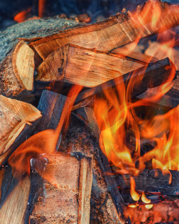 Stack of firewood in front of a glowing fireplace. Warm and cozy ambiance.