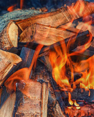 Stack of firewood in front of a glowing fireplace. Warm and cozy ambiance.