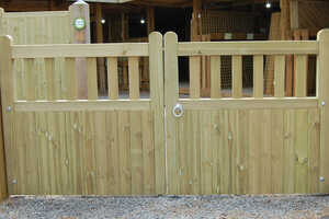 Shop Banff Driveway Gate Wooden Banff driveway gate with an arched top, secured with metal latches in a gravel area.