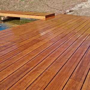 Bamboo decking with smooth planks, extending over water and surrounded by dry grass.