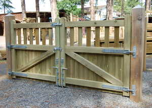Reverse view of Banff double driveway gate with metal latches, set in a gravel pathway surrounded by trees.