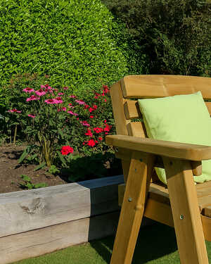 Wooden bench with green cushions in a flower garden with colorful blooms.