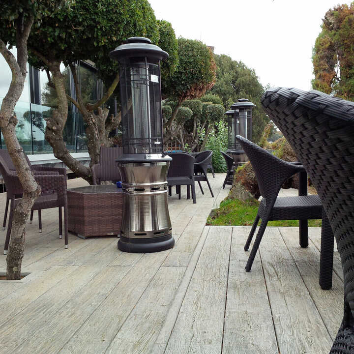 Millboard Weathered Oak deck with seating, patio heaters, and landscaped greenery.