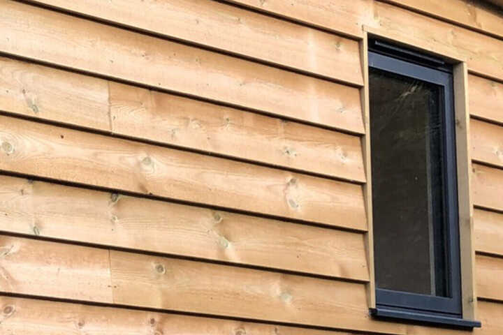 Wooden exterior wall with horizontal cladding and a small black-framed window.