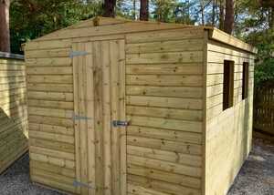 Wooden garden shed with a slanted roof, two windows, and double doors in a gravel area.