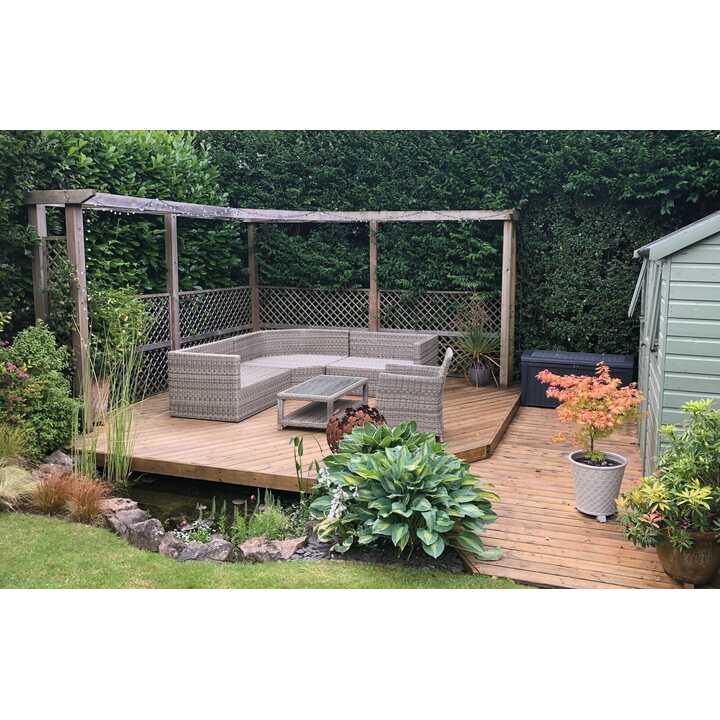 Wooden deck with seating area, greenery, and a small storage shed.