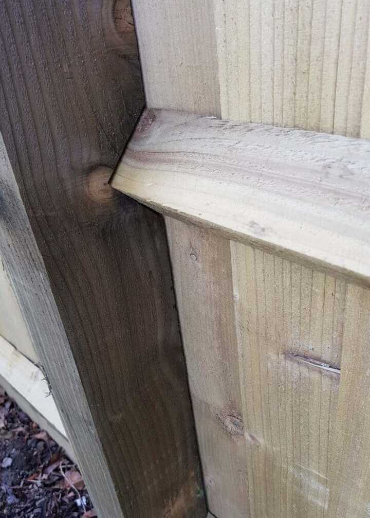 Close-up of a wooden fence showing the notched joint between two planks.
