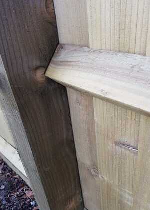 Close-up of a wooden fence showing the notched joint between two planks.