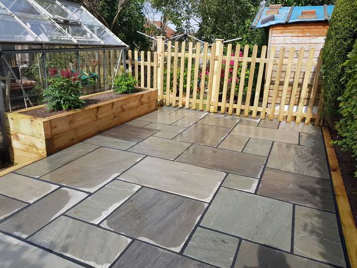 Close-up of a paintbrush applying orange paint on textured wood.