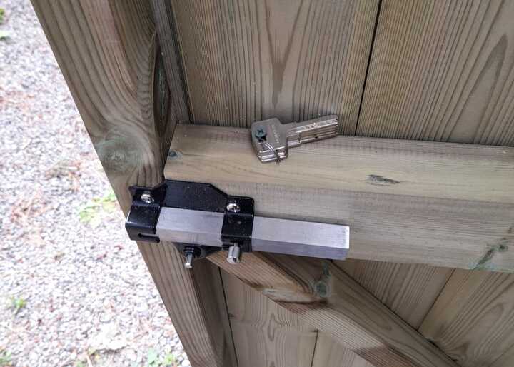 Close-up of the inside of a wooden shed door with a lock and key attached.