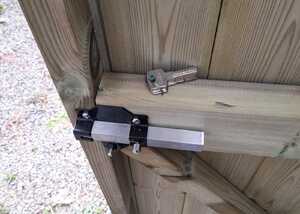 Close-up of the inside of a wooden shed door with a lock and key attached.