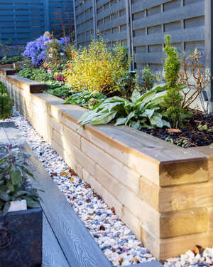 Wooden planter boxes with various plants in a landscaped garden.
