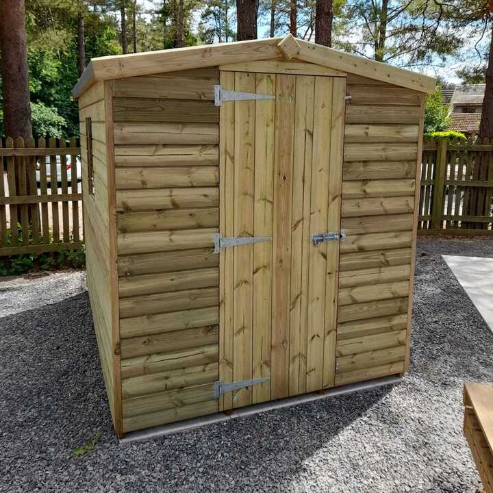 Blue chairs and a table on a timber deck surrounded by plants and flowers.