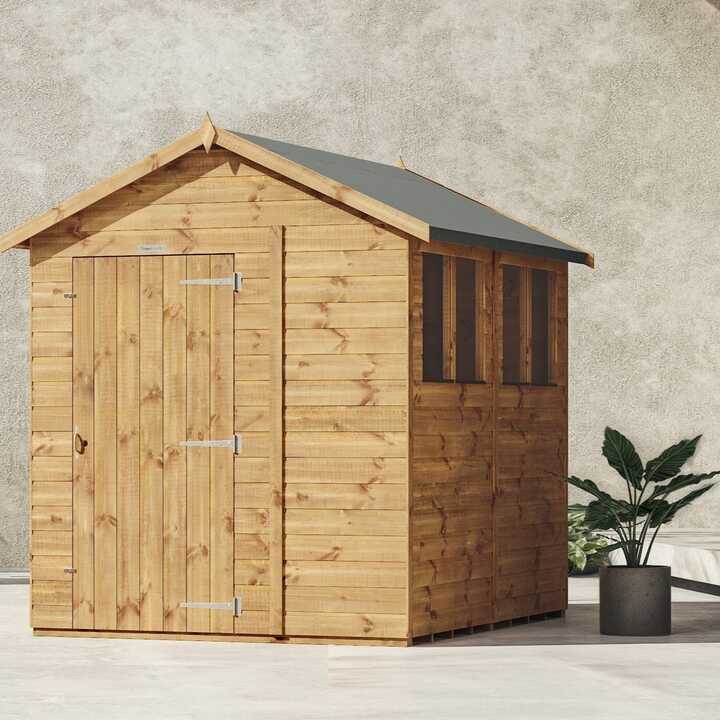 Apex Powershed with a sloped roof and windows, beside a potted plant.