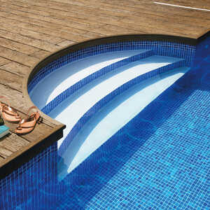 Close-up of a swimming pool with steps and sandals on a curved-edge Millboard composite deck.